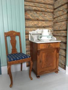 een wastafel en een stoel naast een houten muur bij Skjeggestad Gjestehus in Ringebu