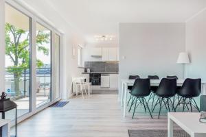 a white kitchen with black chairs and a table at Apartament Nowa Flotylla by Renters in Świnoujście