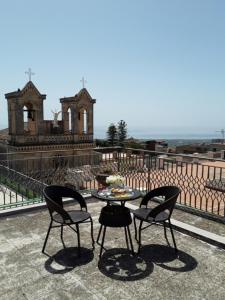 una mesa y 2 sillas en un balcón con un edificio en B&B La Giara, en Piedimonte Etneo