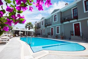 a swimming pool in front of a building with purple flowers at Kapya Cunda in Ayvalık
