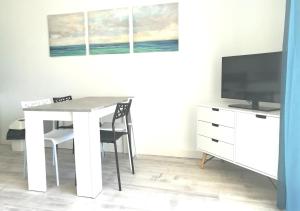 a dining room with a white table and a tv at Appartement 4 couchages, 100 mètres de la mer ! in Les Sables-dʼOlonne
