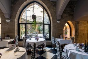 restauracja z białymi stołami i krzesłami oraz dużymi oknami w obiekcie Parador de Hondarribia w mieście Hondarribia
