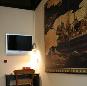 Zimmer mit einem TV und einem Gemälde an der Wand in der Unterkunft HIP Hotel in Heidelberg