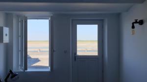 a room with two windows and a door with a view of the beach at Vue d'ici in Saint-Valéry-sur-Somme