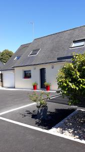 a white building with two potted plants in a parking lot at Auprès de mon arbre in Saint-Gildas-de-Rhuys