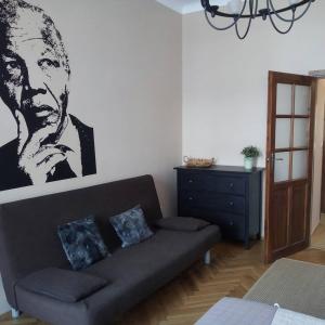 una sala de estar con sofá y una foto de un hombre en Nobel Suites, en Cracovia