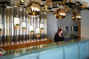 a woman sitting at a counter in a room with chandeliers at Hotel Praia Marina by RIDAN Hotels in Praia da Vitória