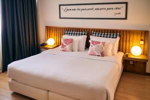 a bedroom with a large white bed with pillows at Hotel Praia Marina by RIDAN Hotels in Praia da Vitória