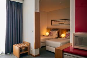 a hotel room with two beds and a television at Hotel Praia Marina by RIDAN Hotels in Praia da Vitória