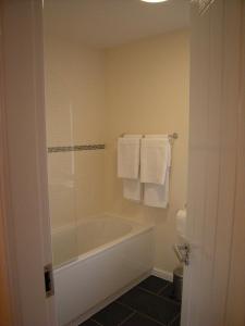a bathroom with a tub and a shower with towels at Knights Rest Conwy Town 5 Star in Conwy