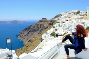 une femme assise sur une corniche donnant sur l'océan dans l'établissement Smaro Studios, à Firostefani