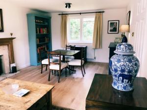 a living room with a table and a blue and white vase at Owlpen Manor Cottages in Uley