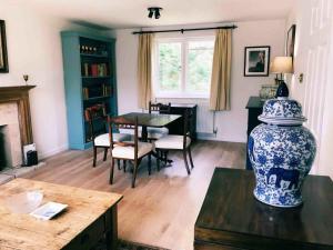 sala de estar con mesa y jarrón azul y blanco en Owlpen Manor Cottages, en Uley