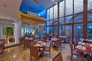 un restaurante con mesas, sillas y ventanas grandes en Hotel Shelton, en Serra Negra