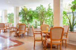 uma fila de mesas e cadeiras numa sala com plantas em Grupotel Taurus Park em Playa de Palma