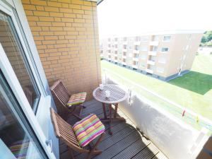 einen Balkon mit 2 Stühlen, einem Tisch und einem Gebäude in der Unterkunft Appartement 206 in Westerland