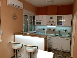 a kitchen with white cabinets and a counter with stools at Apartment Centar Exclusive Smederevo in Smederevo