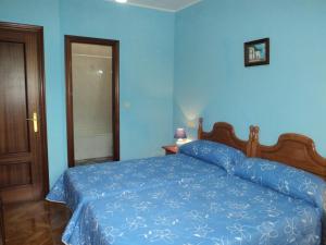 a blue bedroom with a bed with a blue comforter at APARTAMENTOS RURALES PERNÚS in Colunga