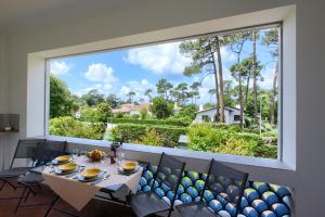 una ventana grande en un comedor con mesa y sillas en Appartement Pyla Les Cèdres, en Pyla-sur-Mer