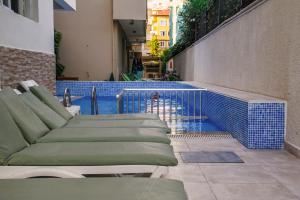 a swimming pool with chaise lounge chairs next to a building at Aysev Hotel in Alanya