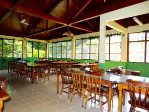 a restaurant with wooden tables and chairs and windows at La Selva Biological Station in Sarapiquí
