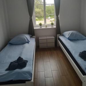 two twin beds in a room with a window at Apartament w starej kamienicy in Mrągowo