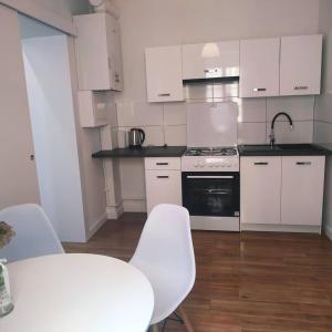 a kitchen with white cabinets and a table and chairs at Apartament w starej kamienicy in Mrągowo