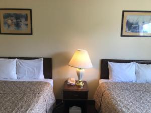 a hotel room with two beds and a lamp on a night stand at Glacier Hotel in Valdez