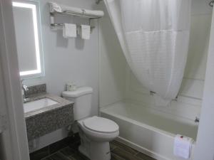 a white bathroom with a toilet and a bath tub at Plum Tree Inn in Williamstown