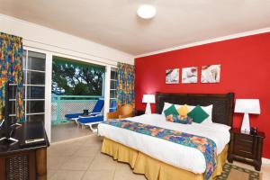 a bedroom with a bed, a desk, and a painting on the wall at Coral Mist Beach Hotel in Bridgetown