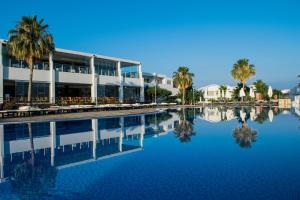 uma piscina com palmeiras e um edifício em Theo Sunset Bay Hotel em Pafos