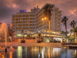 un gran edificio con palmeras delante en H10 Tenerife Playa, en Puerto de la Cruz