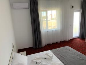 a bedroom with a white bed with a window at Casa Margo in Eforie Nord