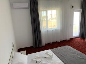 um quarto com uma cama branca e uma janela em Casa Margo em Eforie Nord