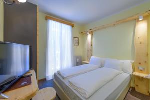 a bedroom with a bed and a flat screen tv at Park Hotel Faloria in Canazei