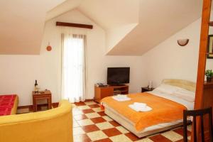 a bedroom with a bed and a tv and a couch at Apartmani Skver Sanja in Herceg-Novi