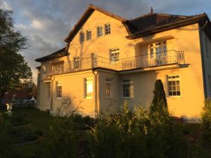 a yellow house with a balcony on top of it at Seehotel Louise in Gransee