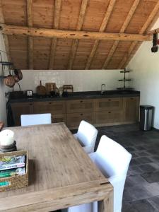 eine Küche mit einem Holztisch und weißen Stühlen in der Unterkunft The Barn in Emst