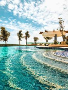 a swimming pool with blue water and palm trees at SALINAS PARK RESORT in Salinópolis +20 photos