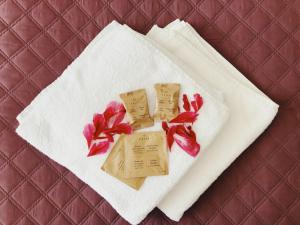 a white towel with red flowers on top of a bed at Sancta Elena in Šventoji