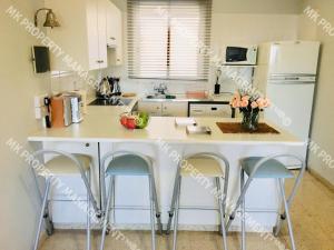 a kitchen with a counter with stools and a refrigerator at Yiallos Village C107 in Larnaca