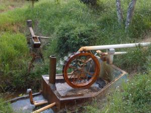 a water pump with a wooden wheel in a field at Fazenda Camping Cabral in São Lourenço