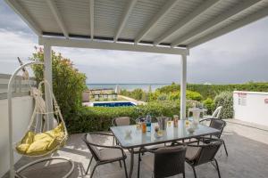 eine Terrasse mit einem Tisch, Stühlen und Meerblick in der Unterkunft Gorgona Villas in Ayia Napa