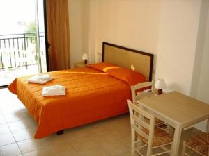 a bedroom with a large orange bed and a table at Margarita Beach Hotel in Agia Marina Nea Kydonias