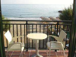 Margarita Beach Hotel في أييا مارينا نيا كيذونياس: طاولة وكراسي على شرفة مع الشاطئ