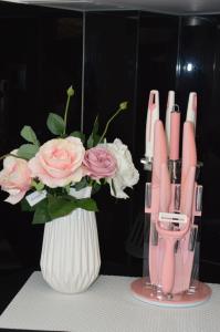 eine Vase mit rosa Stiften und einem Strauß rosa Rosen in der Unterkunft S. Luxury Princess Suite in Nea Kallikratia