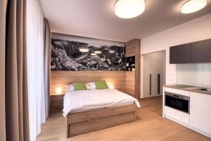 1 dormitorio con 1 cama con una pintura en la pared en Trio Tatry, en Starý Smokovec