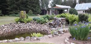 a garden with a pond and rocks and flowers at Metsjärve kämpingumajake in Puskaru