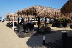 a beach with tables and chairs under a straw umbrella at 2 Zimmer Wohnung in Sunny Beach
