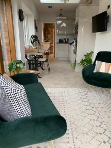 a living room with a green couch and a kitchen at The Folly in Ludlow